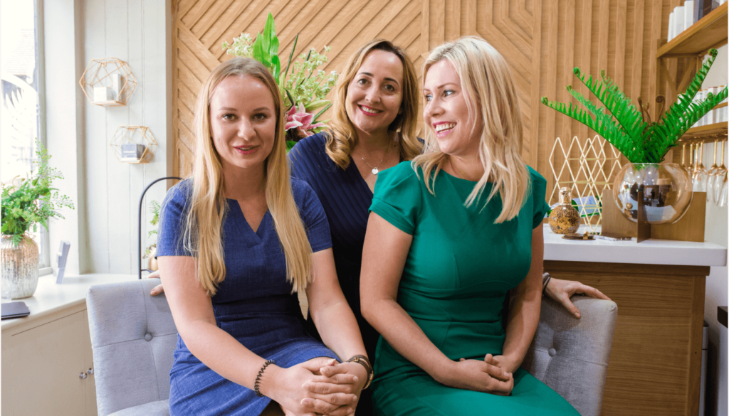 Invest time in your team. An image of a happy salon team seated together smiling. 